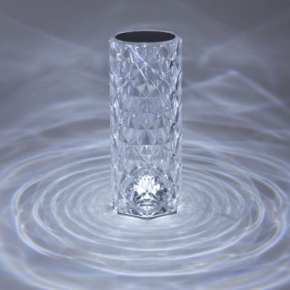 Cylindrical crystal LED lamp illuminated with cool white light casting decorative reflections for modern bedside or restaurant lighting.