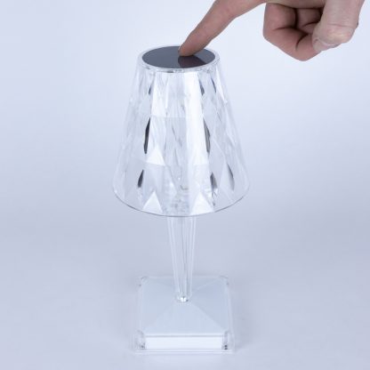 Hand touching the top of the crystal touch lamp to activate LED light, demonstrating touch control feature on diamond pattern lamp.