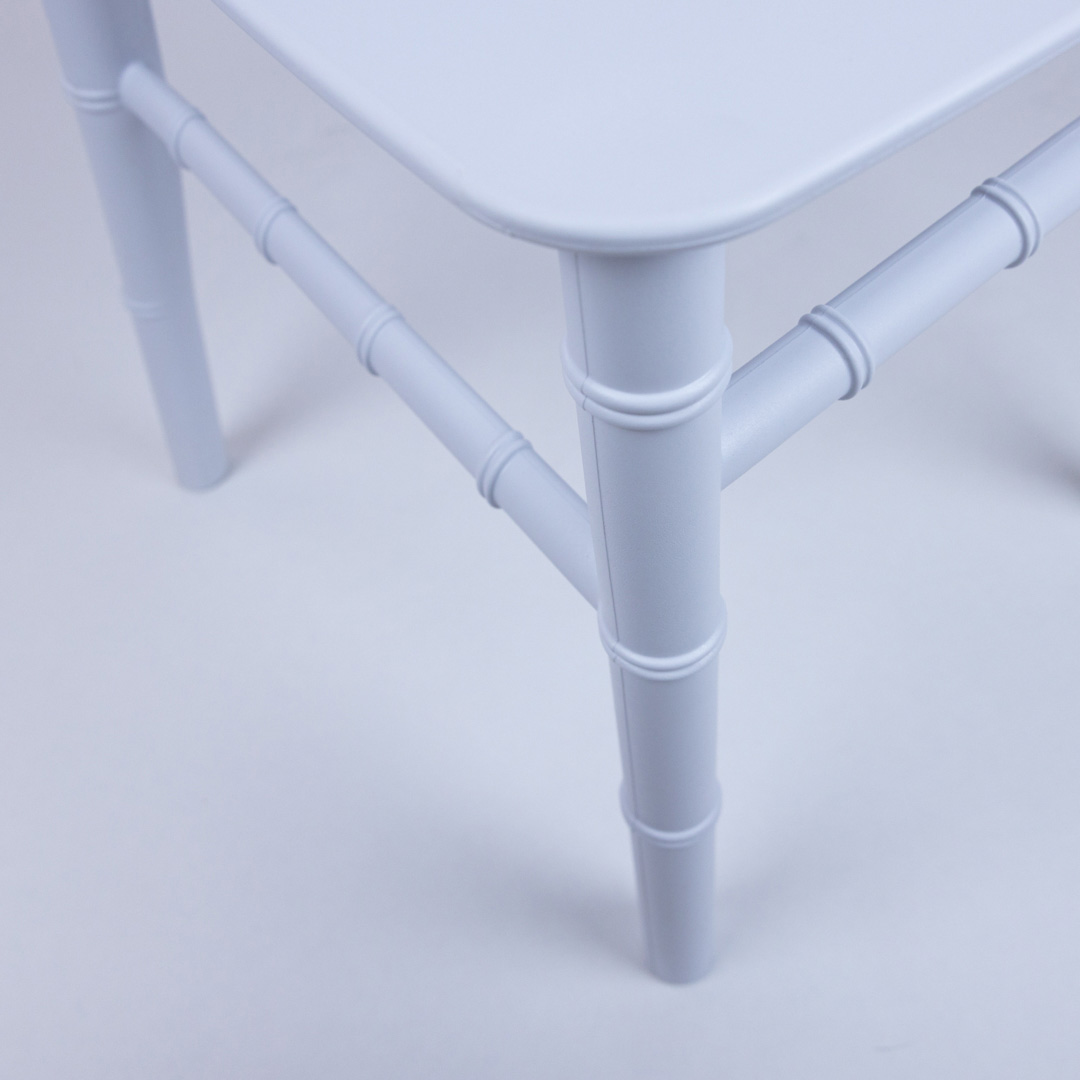 Close-up of the leg and frame design on the white resin child Napoleon chair, showing strong, stackable construction ideal for event hire use.