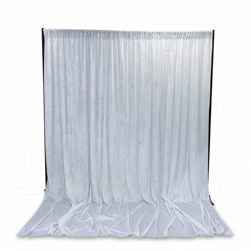 Full white crushed velvet backdrop curtain displayed on stand with puddled drape at base